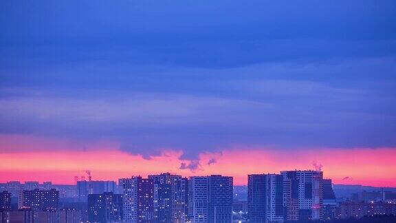 灯光照亮了夜晚的窗户城市的房子和汽车行驶的道路时光流逝俄罗斯现代莫斯科粉红色的晚霞黄昏时城市的顶视图