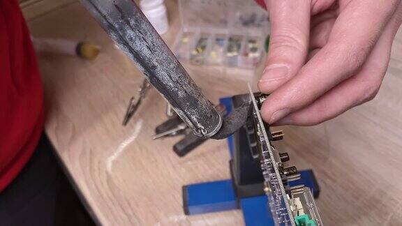 一个工匠的手焊接两根电线的极端特写车间的焊接过程