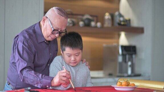 亚洲华人小男孩向他的祖父学习写中国书法