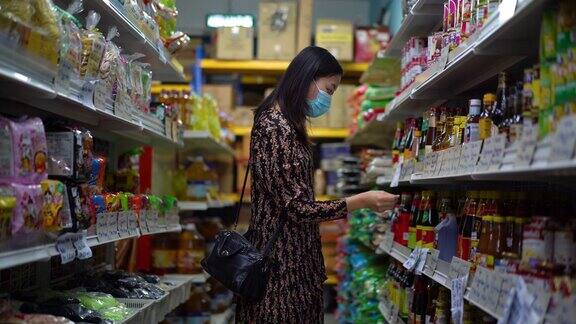 年轻的亚洲妇女戴着防护口罩在超市购物