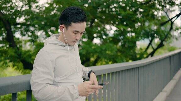 年轻的亚洲运动员在公园里使用智能手机