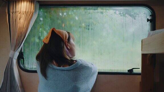 孤独的女人透过窗户看着雨