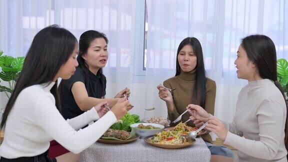 一群年轻的亚洲女性朋友坐在一起吃传统的亚洲食物如泰国当地食物