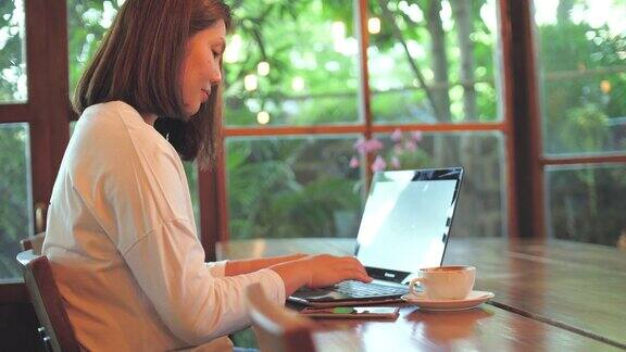 女人用笔记本电脑工作在咖啡馆喝咖啡