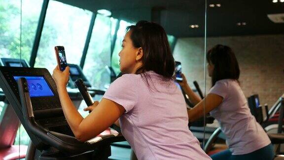 商务女性在健身房锻炼用智能手机自拍