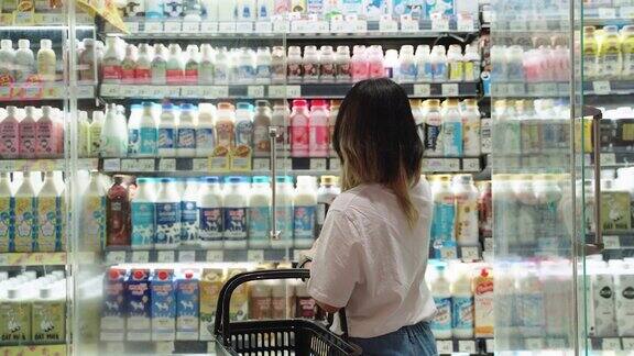在货架上挑选新鲜牛奶的妇女