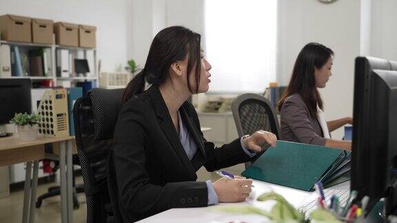 亚洲女性在下班时间从经理和同事那里得到更多的工作她看着别人离开办公室脸上带着困惑的表情