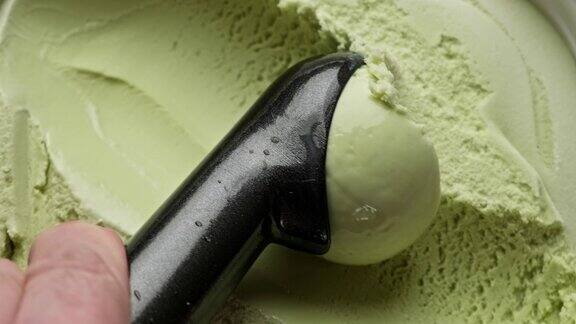 用勺子从容器中舀出口味的开心果冰淇淋