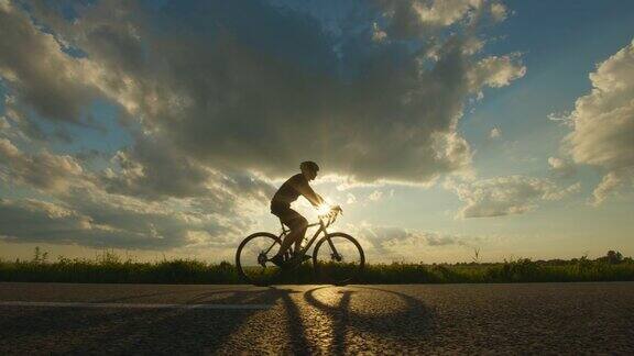 一个骑自行车的人正在高速公路上骑自行车夕阳在背景中镜头向后移动4k