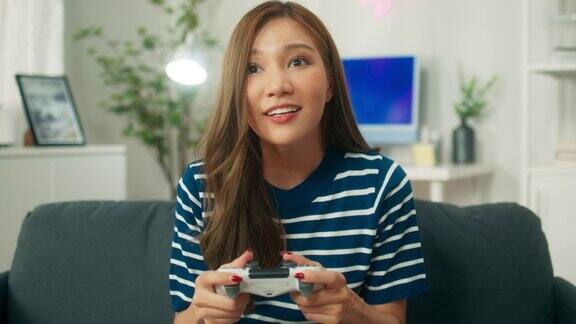 迷人的年轻亚洲女子玩游戏使用无线操纵杆控制器