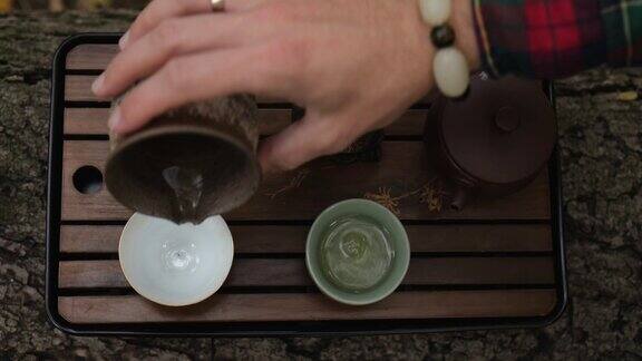 特写镜头一个男人的手往碗里倒黑普洱茶户外茶道