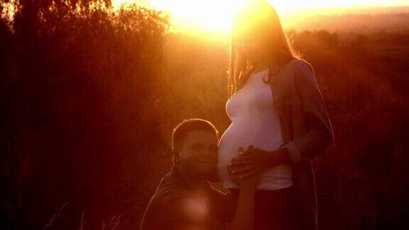 怀孕时她的伴侣抱着她把她的肚子放在户外