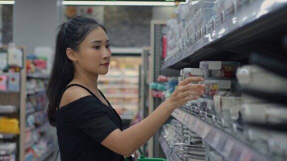 年轻女性在商店里看着商品并阅读标签在超市选购蔬菜、水果和购物的人