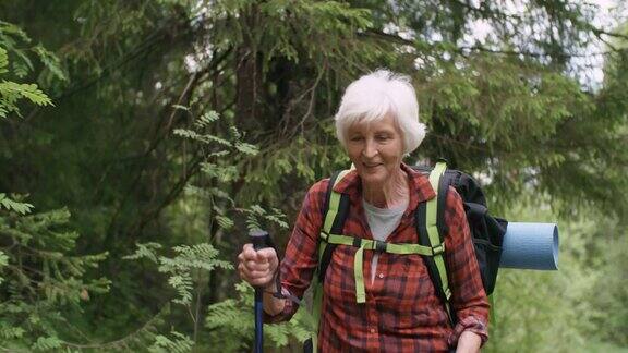 快乐的老年女性徒步者与徒步杆子