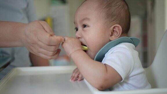母亲在家里的厨房里给她的男婴喂第一顿饭