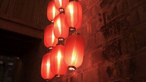 晚上有中国寺庙的底层石墙和阳台特写点燃的红灯笼悬挂在屋顶的柱子上照亮灯光传统装饰东方节日庆典