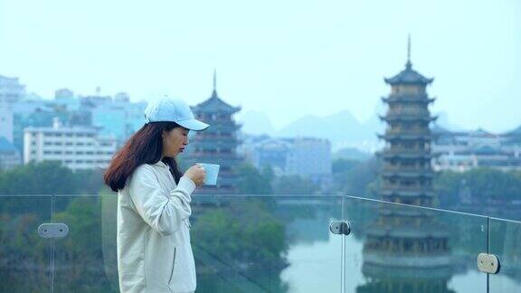 在中国桂林市中心年轻的女子一边喝着咖啡一边看着宝塔