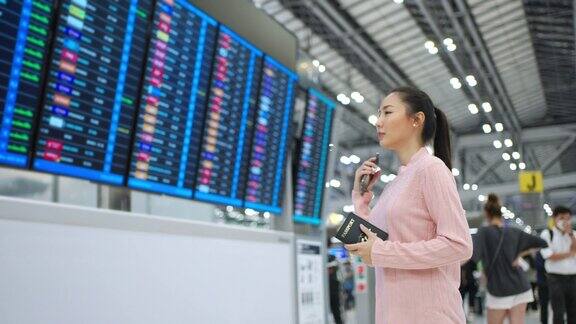 4K亚洲女子在机场候机楼查看时刻表