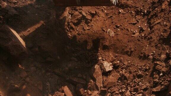 慢动作镜头的一桶挖掘机挖掘和捡起泥土在一个阳光明媚的建筑工地