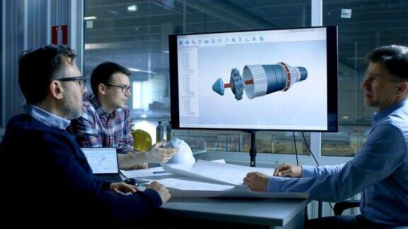 工业工程师小组讨论三维模型的涡轮发动机设计显示在演示显示在背景工厂被看到