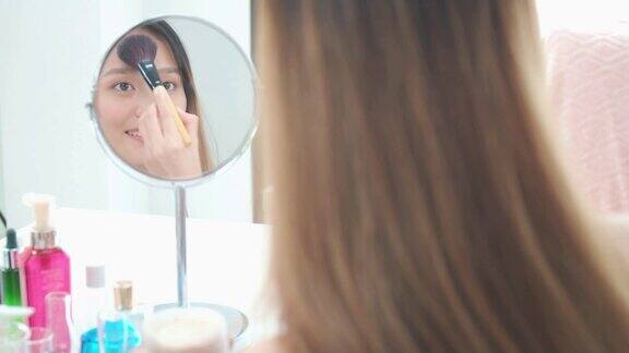 美丽的亚洲女人博客展示如何化妆和使用化妆品在家里的镜子前商业在线影响者对社交媒体
