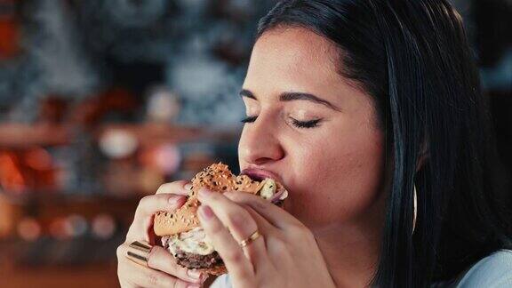 一个年轻女子在餐厅里吃汉堡的4k视频