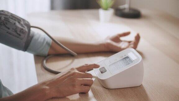 亚洲妇女用数字血压仪测量自己的血压