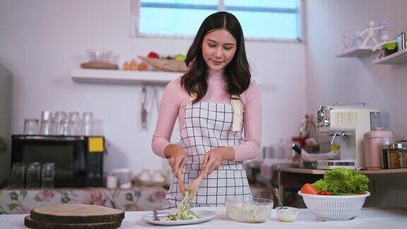 年轻健康的亚洲妇女微笑的家庭主妇准备健康的膳食素食健康吃新鲜蔬菜沙拉在厨房