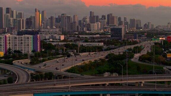 日落时分从美国佛罗里达州北迈阿密的高架十字路口以及繁忙的95号州际公路眺望迈阿密市中心用无人机拍摄的后向镜头