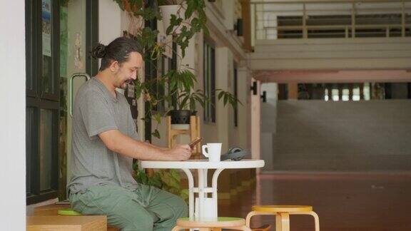亚洲男性坐在咖啡店里使用手机