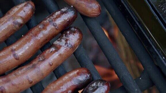 在森林露营时在火坑烧烤架上烤着美味的烧焦热狗