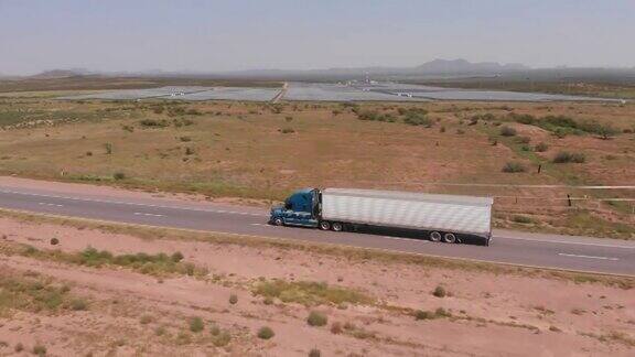 无人机拍摄的一辆长途半挂车在墨西哥高速公路上超速行驶经过一座太阳能发电站