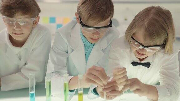 男孩们在实验室里做科学实验用移液管混合多种颜色的液体近距离