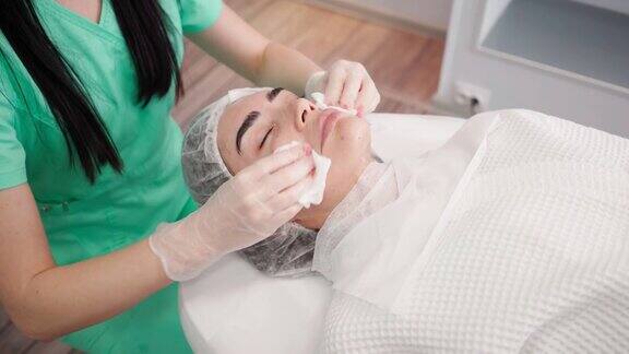 女性美容师在美容院为女性病人做面部皮肤护理程序