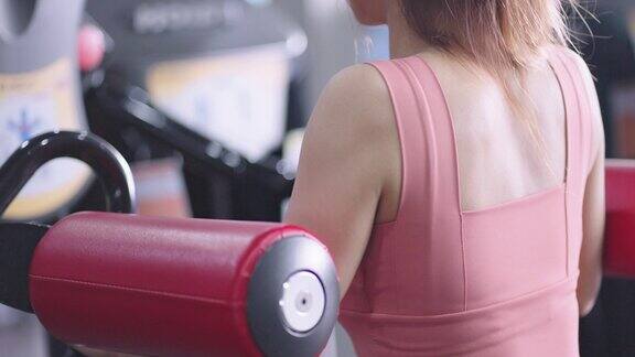 不认识的女人在健身房使用肩部锻炼机