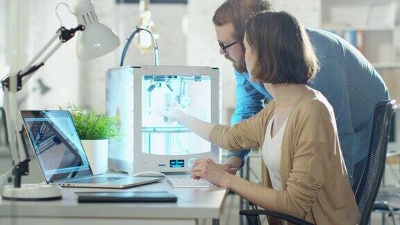 年轻的男和女工程师使用3D打印机创建模型
