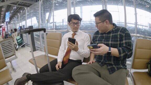 两个亚洲朋友聊着什么然后其中一个离开去机场登机口旅行了