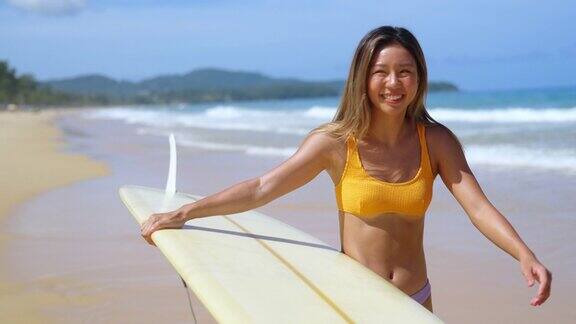 4K亚洲妇女拿着冲浪板走到海洋在夏天阳光明媚的一天