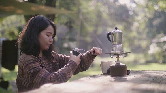 森林里的一个年轻女子正坐在木桌上准备煮咖啡