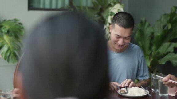 亚洲多代家庭团聚在饭桌上聊天分享故事和食物在前院吃饭