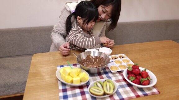 年轻的母亲和她的小女儿在家里做巧克力挞