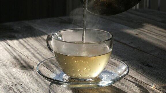 将绿茶从茶壶中倒进玻璃杯中