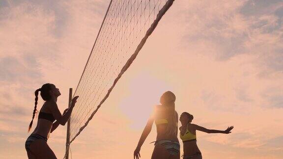 性感的排球女孩穿着比基尼在沙滩上玩夏日排球在日落的慢动作