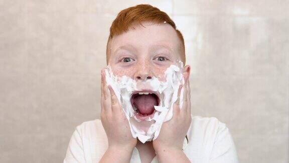 那男孩在脸颊上抹了刮胡子泡沫洗澡的滑稽男孩用剃须膏涂在脸上孩子模仿成年父亲刮胡子