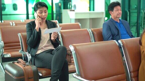 商务女性在机场等待办理登机手续时会给同事打手机也会查看登机牌上的详细信息