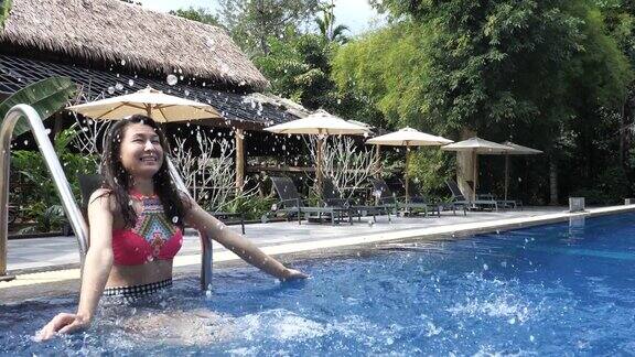 亚洲快乐女人游泳和放松在度假酒店的游泳池