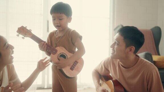音乐时刻:亚洲父母和孩子在家里享受吉他游戏时光