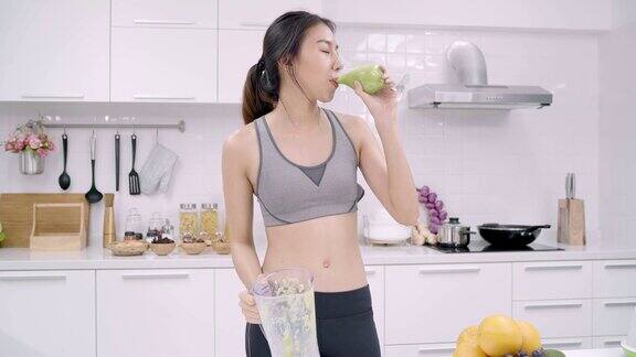 运动的亚洲女人在厨房喝苹果汁美丽的女性在运动服装使用有机水果大量营养在家里自己做苹果汁健康食品