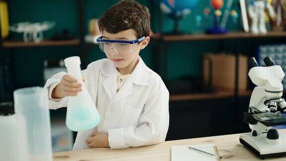 可爱的西班牙男孩学生在实验室教室里取出试管上的液体