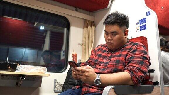 一名亚洲男子在火车上使用手机